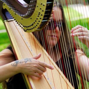 Terri Langerak plays the harp in an outdoor setting.