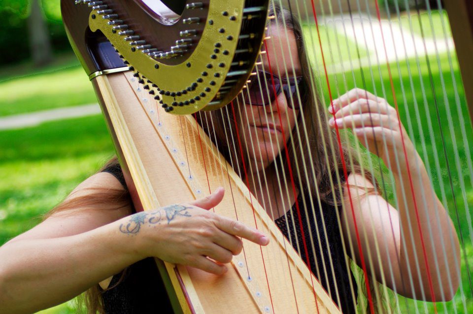 Terri Langerak plays the harp in an outdoor setting.