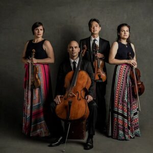 Jupiter String Quartet, posing formally with their instruments in a dramatically-lit studio photo.