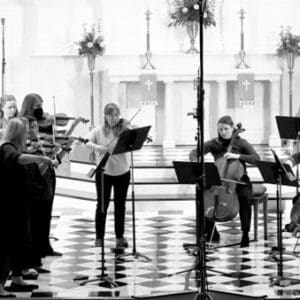 St. Louis Chamber Soloists performing around music stands in a casual setting.
