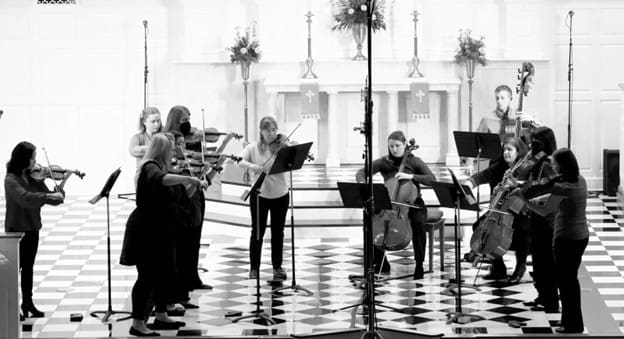 St. Louis Chamber Soloists performing around music stands in a casual setting.