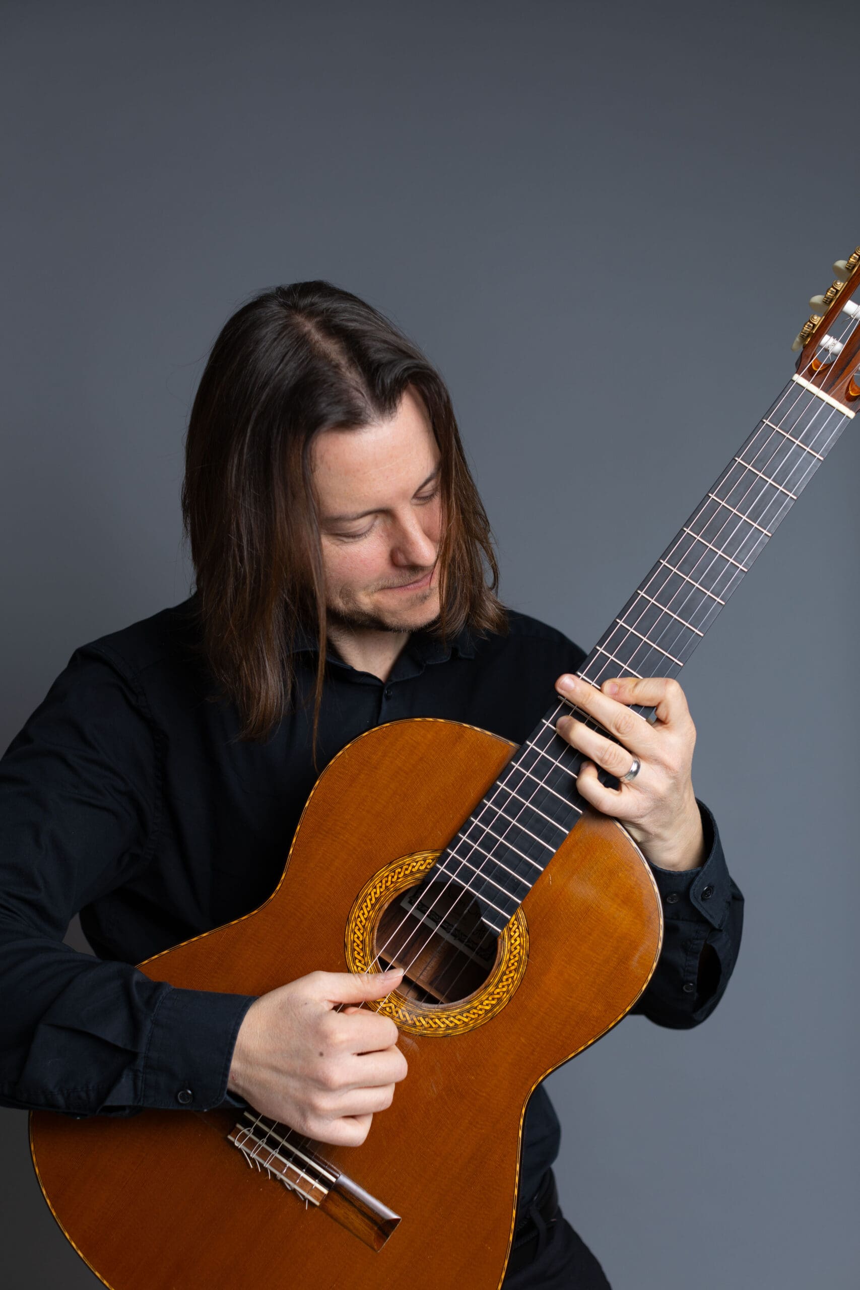 W. Mark Akin posing with his guitar in a studio setting.