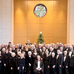 Chancel Choir posing in concert attire in front of a christmas tree.